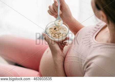 Selective Focus, Topview Of  A Pregnant Woman Holding A Bowl Of Yogurt On Top Of Granola For Her Bab
