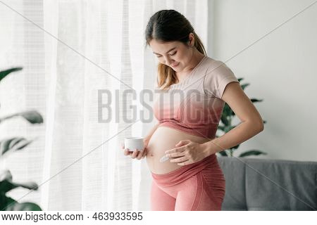 Beautiful Pregnant Asian Woman Is In Exercise Outfits, Applying Pregnancy Stretch Mark Protection Cr