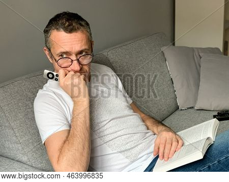 Self Isolation In Small Flat, Mentally Burned Out Man Sitting On Sofa At Home, Bored Of Streaming An