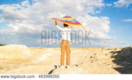 A Boy Of 8-9 Years Old Happily Launches Kite Into The Sky.