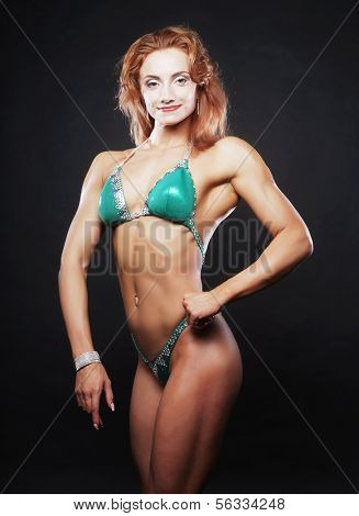 A beautiful woman bodybuilder posing in green  bikini