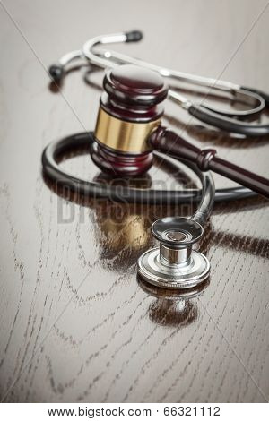 Gavel and Stethoscope on Reflective Wooden Table.