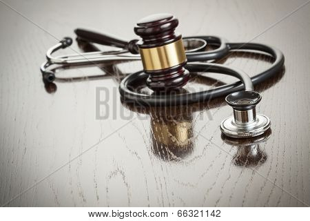 Gavel and Stethoscope on Reflective Wooden Table.