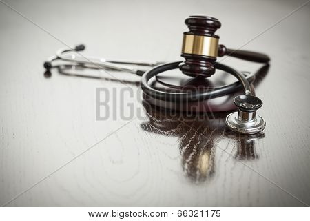 Gavel and Stethoscope on Reflective Wooden Table.