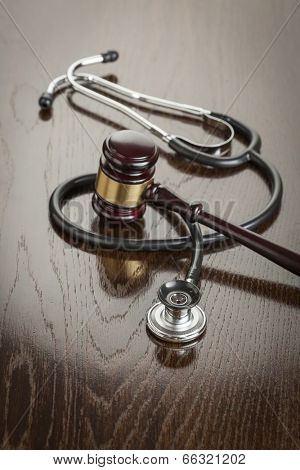 Gavel and Stethoscope on Reflective Wooden Table.