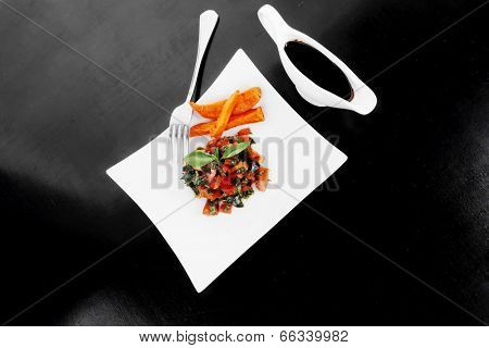 vegetable salad : cherry tomatoes and basil with sweet baked potato served on white plate with sauceboat full blask soy sauce on wood