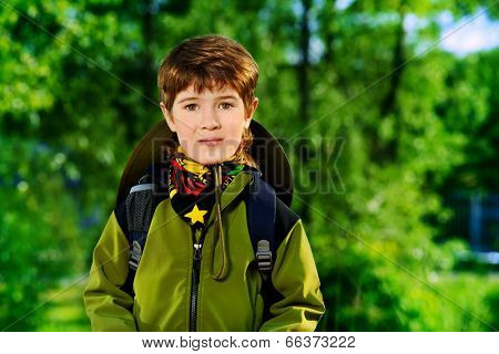 Portrait of a cute 7 years old boy in tourist clothes posing outdoor. Summer day. 