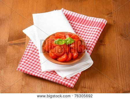 portion of halved cherry tomatoes with basil, served in the bowl with two kinds of fabric linen