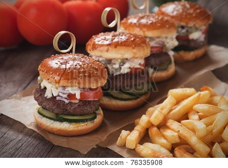 Mini hamburgers with french fries served as appetizer on wooden table