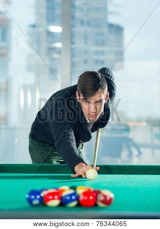 Young man playing billiards in billiard club