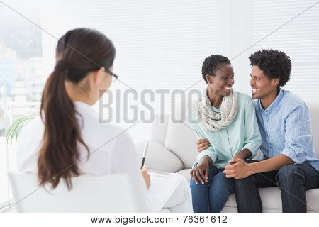 Reconciled couple smiling at each other in therapists office