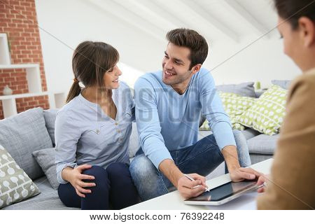 Young couple signing financial contrat on digital tablet