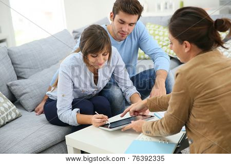 Young couple signing financial contrat on digital tablet