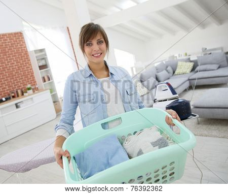 Young home service woman holding basket of folded laundry