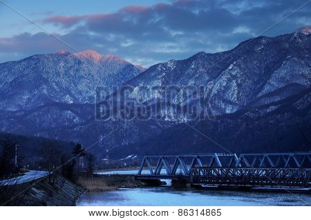 Railroad Bridge through the Carpathian Mountains, passing by the Olt Valley, Romania - sunset blue hour light