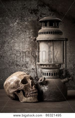 still life with skull human and old hurricane lamp