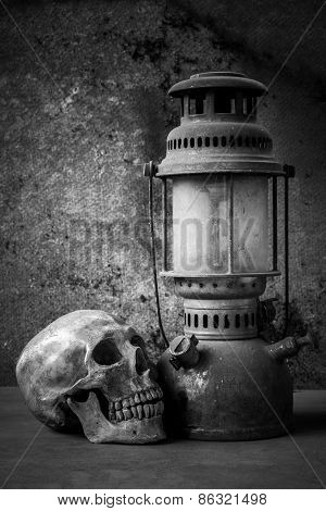 still life with skull human and old hurricane lamp