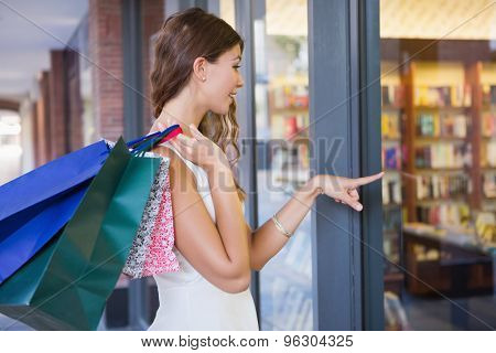 Smiling Woman with shopping bags pointing the window at the shoppingmall