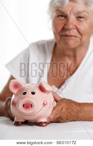 Elder woman holding and hugging funny pink piggybank
