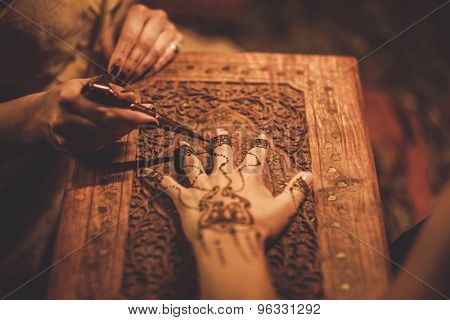 Drawing process of henna menhdi ornament on woman's hand 