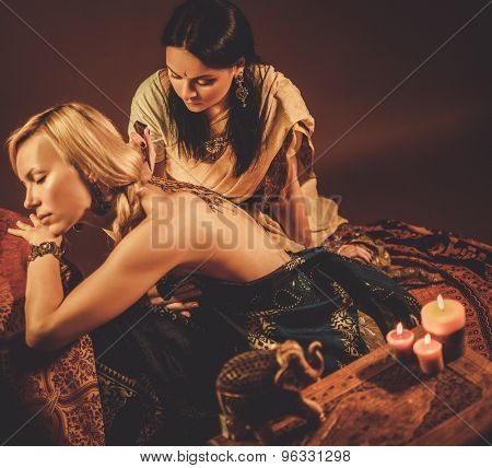 Drawing process of henna menhdi ornament on woman's back 