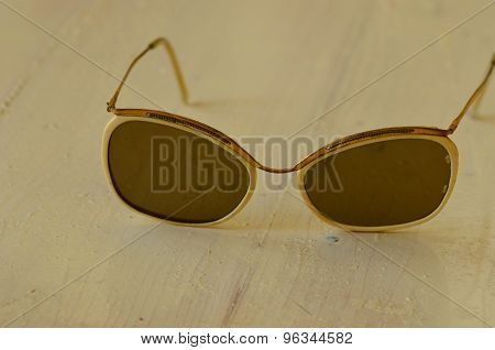 Retro white sunglasses on white wooden background.