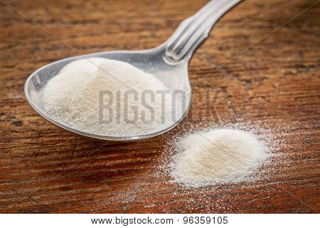 collagen protein powder on a tablespoon against rustic wood