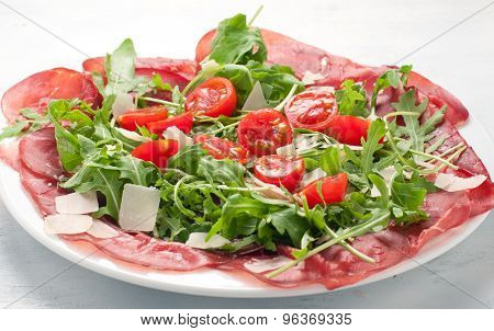 Plate of bresaola with rocket parmesan and cherry tomatoes l