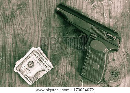 The gun and money on wooden table. Concepts: crime contract killing killer robbery extortion money laundering.