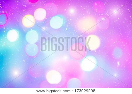 Defocused colorful ligths of Christmas tree. Multicolored bokeh lights during a snowfall. Background for greeting card. Winter composition. Happy holiday mood. Xmas and New Year fairy tale wallpaper.