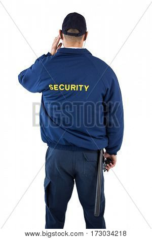 Rear view of security officer listening to earpiece against white background
