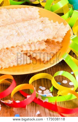 Carnival pastry with confetti on wooden table.