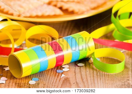 Carnival pastry with confetti on wooden table.