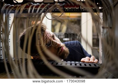 Technician checking cables in a rack mounted server in server room
