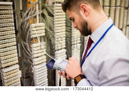 Technician using digital cable analyzer in server room