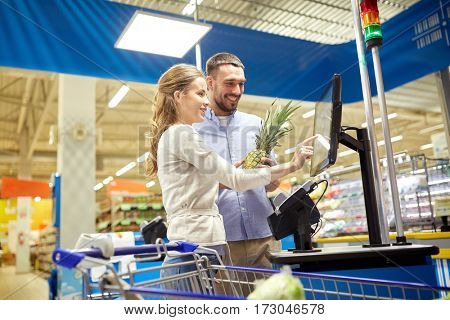 shopping, sale, consumerism and people concept - happy couple buying food at grocery store or supermarket self-service cash register
