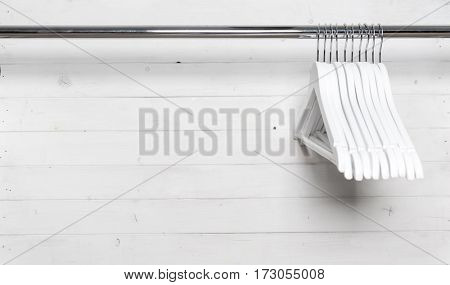 Stack of white wooden hangers on one side of the hangning rack, monochrome