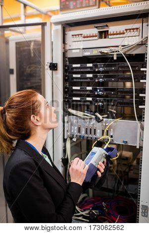 Technician using digital cable analyzer in server room
