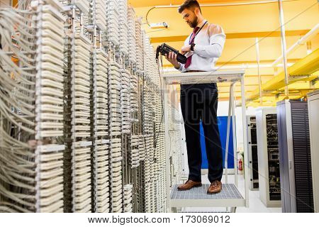 Technician using digital cable analyzer in server room