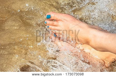 Woman's leg lay on white plastic armchair on the wet beach in hot sunny time with shadow beside the blue sea