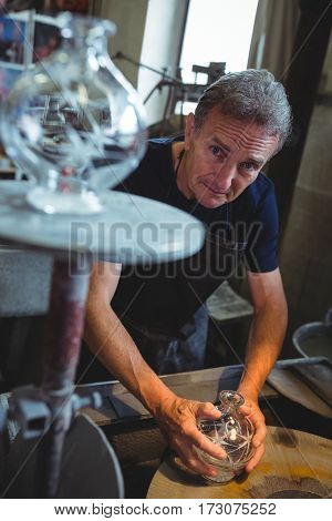Portrait of glassblower working on a glass at glassblowing factory