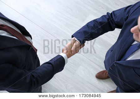 Employer and applicant shaking hands after interview, top view