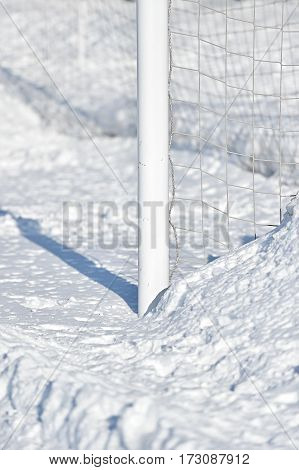 Detail with a soccer goalpost covered by snow