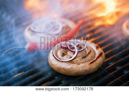 cumberland sausage, spiral pork sausage on bbq grill with flame, homemade