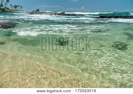 Sunny beach near Koggala - Sri Lanka The area famous for its distinct stilt fishermen, who erect a single pole in the chest-deep water on the beach, just few meters off-shore. Splittoned, vivid image.