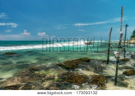 Sunny beach near Koggala - Sri Lanka The area famous for its distinct stilt fishermen, who erect a single pole in the chest-deep water on the beach, just few meters off-shore. Splittoned, vivid image.