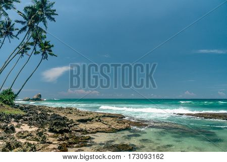 Sunny beach near Koggala - Sri Lanka The area famous for its distinct stilt fishermen, who erect a single pole in the chest-deep water on the beach, just few meters off-shore. Splittoned, vivid image.