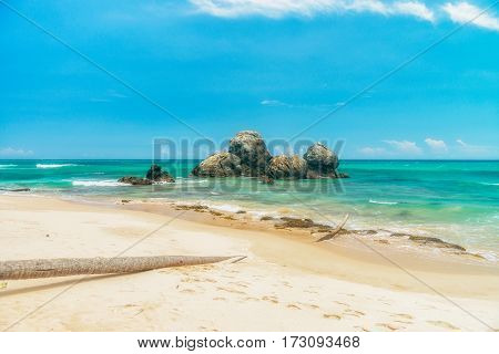 Sunny beach near Koggala - Sri Lanka The area famous for its distinct stilt fishermen, who erect a single pole in the chest-deep water on the beach, just few meters off-shore. Splittoned, vivid image.