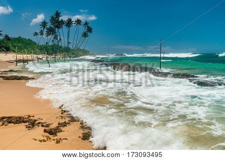 Sunny beach near Koggala - Sri Lanka The area famous for its distinct stilt fishermen, who erect a single pole in the chest-deep water on the beach, just few meters off-shore. Splittoned, vivid image.