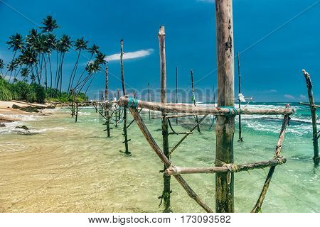 Sunny beach near Koggala - Sri Lanka The area famous for its distinct stilt fishermen, who erect a single pole in the chest-deep water on the beach, just few meters off-shore. Splittoned, vivid image.
